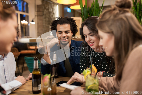 Image of happy friends with drinks and bill at bar or cafe