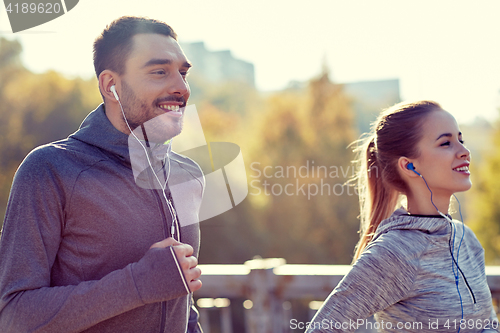 Image of happy couple with earphones running in city