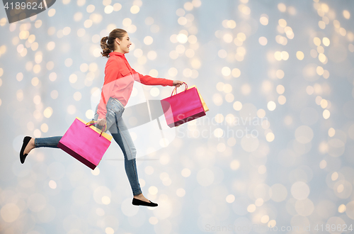 Image of smiling young woman with shopping bags running