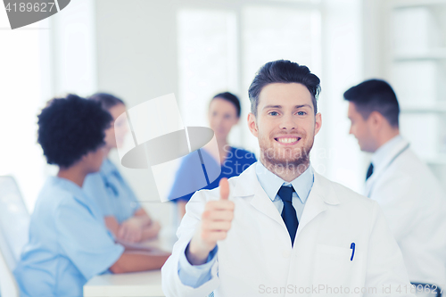 Image of happy doctor over group of medics at hospital