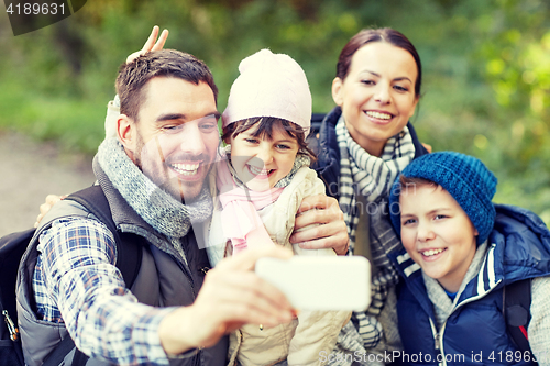 Image of family taking selfie with smartphone in woods