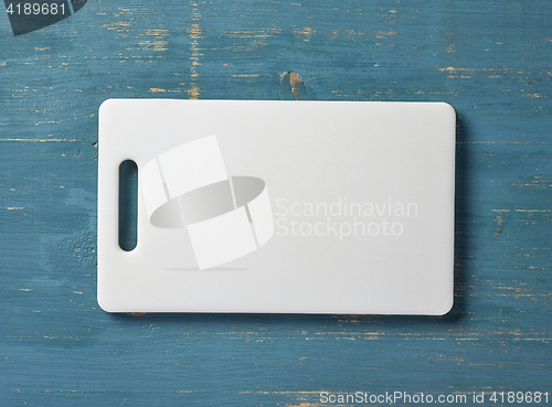 Image of white plastic cutting board on blue table