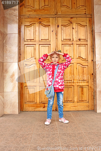 Image of Schoolgirl posing before big wooden door