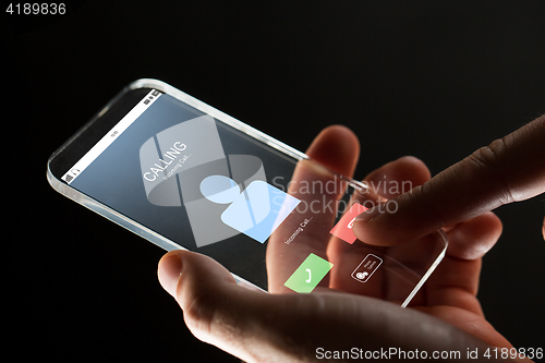 Image of close up of hand with incoming call on smartphone