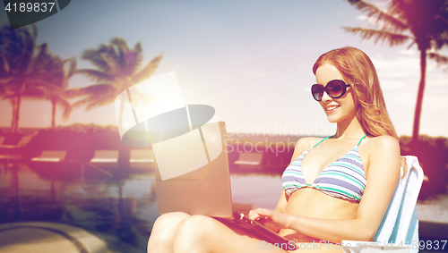 Image of happy young woman in shades with laptop on beach