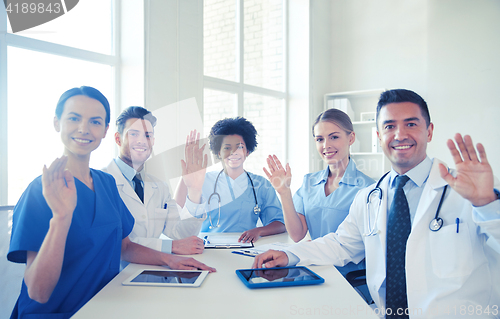 Image of happy doctors meeting and waving hands at hospital