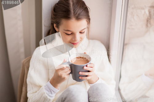 Image of girl with cacao mug sitting at home window