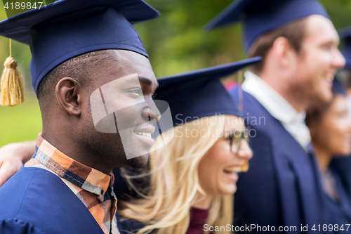 Image of happy students or bachelors in mortar boards