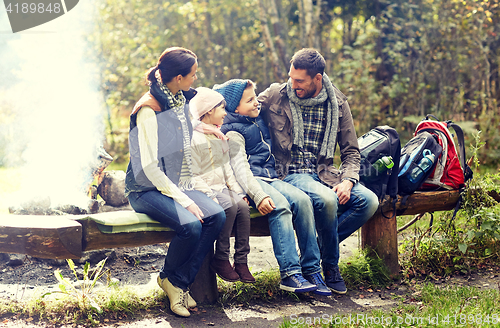 Image of happy family sitting on bench and talking at camp