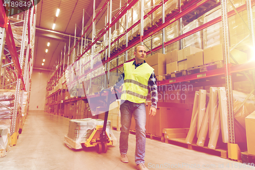 Image of man carrying loader with goods at warehouse