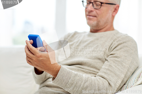 Image of close up of senior man with smartphone at home