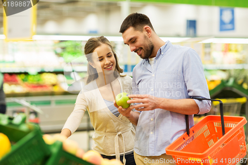 Image of happy couple buying apples at grocery store