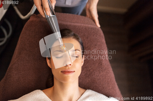 Image of woman with microcurrent face massager in spa