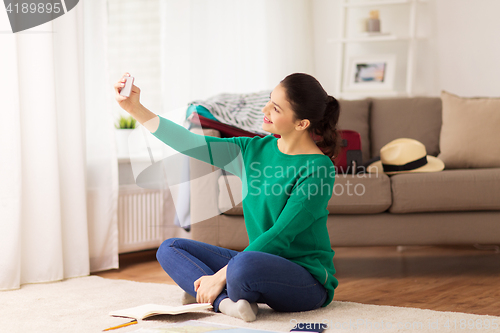 Image of woman with smartphone taking selfie at home