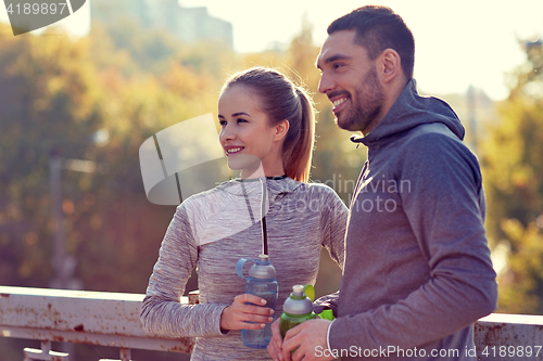 Image of smiling couple with bottles of water outdoors