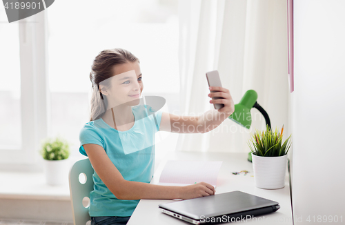 Image of happy girl with smartphone taking selfie at home