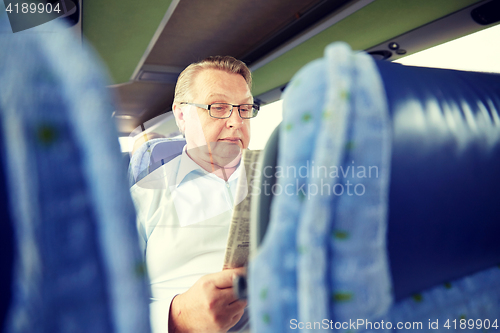 Image of happy senior man reading newspaper in travel bus