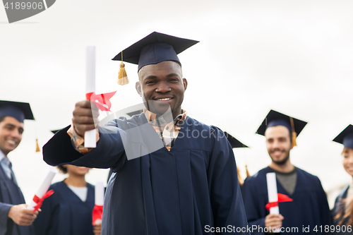 Image of happy students in mortar boards with diplomas