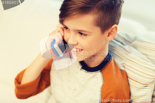 Image of happy boy calling on smartphone at home