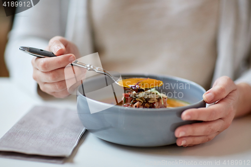 Image of woman eating pumpkin cream soup at restaurant