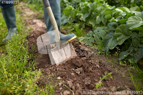 Image of farmer with shovel digging garden bed or farm