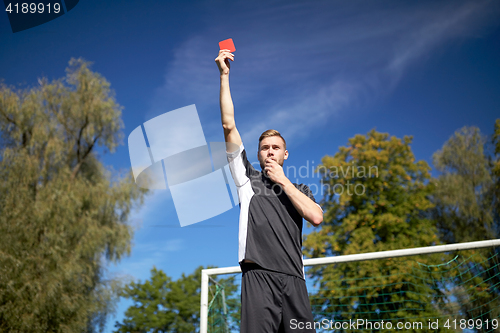 Image of referee on football field showing yellow card