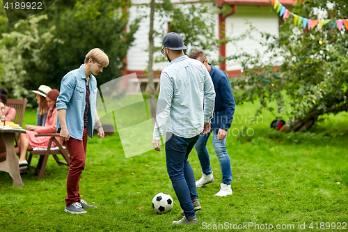 Image of happy friends playing football at summer garden