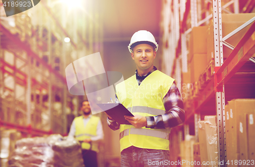 Image of man with clipboard in safety vest at warehouse