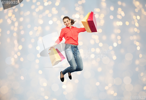 Image of smiling young woman with shopping bags jumping