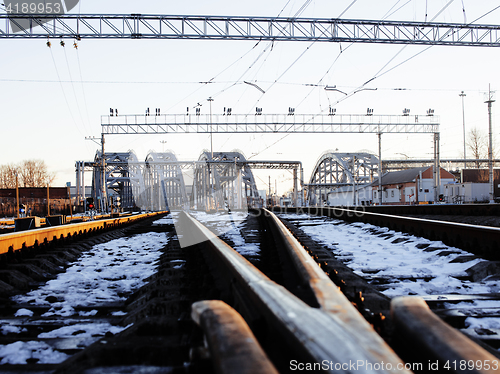 Image of landscape with railway with trains, lot of steel rafters at sunset