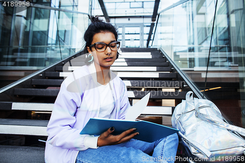 Image of young cute indian girl at university building sitting on stairs 