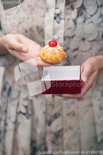 Image of Woman holding eclair and red box