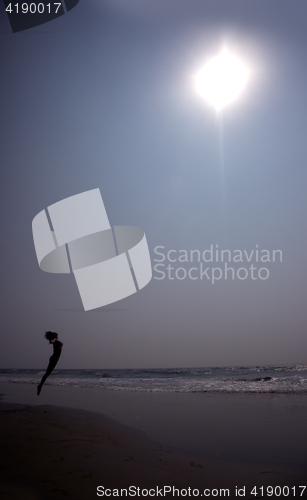 Image of Silhouette of the jumping lady at the summer beach. Artistic col