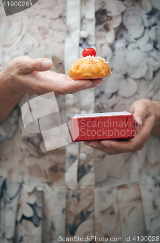 Image of Woman holding eclair and red box