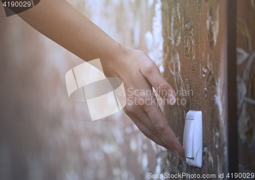 Image of Woman turning on or off electric switch