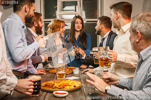 Image of Group of friends enjoying evening drinks with beer