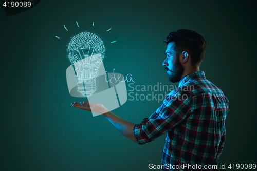 Image of Handsome young man with idea bulb on blue