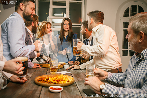 Image of Group of friends enjoying evening drinks with beer