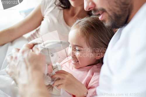 Image of happy child with toy and parents in bed at home