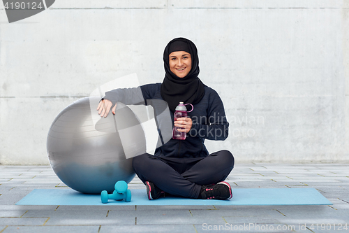 Image of muslim woman in hijab with fitness ball and bottle