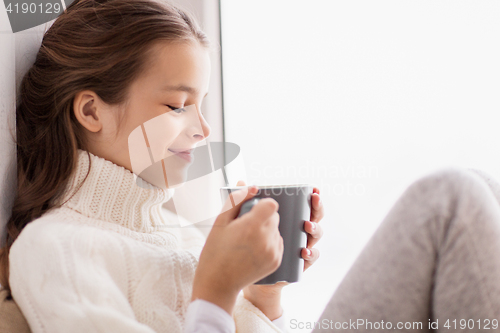 Image of girl with tea mug sitting at home window