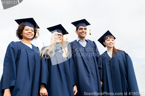 Image of happy students or bachelors in mortarboards
