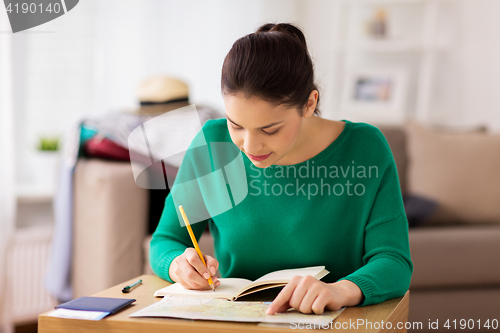 Image of woman with notebook and travel map at home