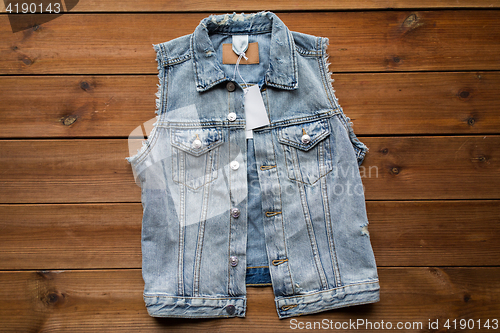 Image of close up of denim waistcoat with price tag on wood