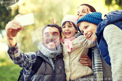 Image of family taking selfie with smartphone outdoors