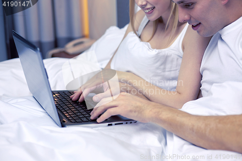 Image of smiling couple in bed with laptop computer