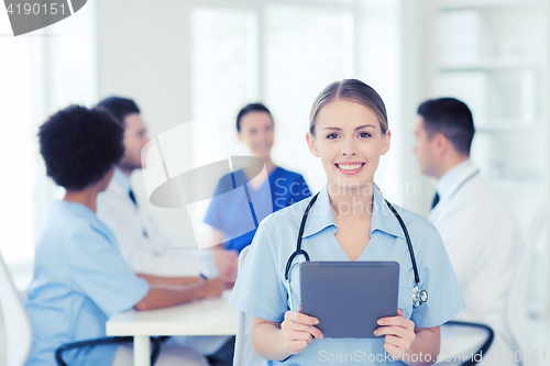 Image of happy doctor with tablet pc over team at clinic