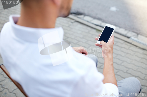 Image of close up of man texting on smartphone in city