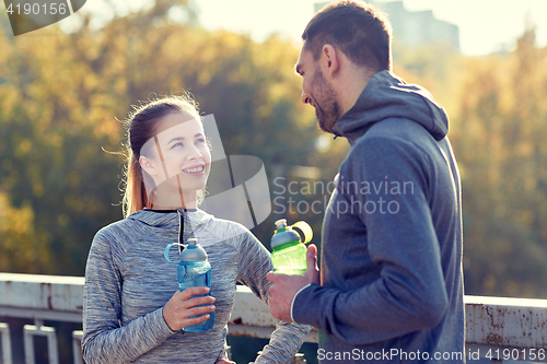 Image of smiling couple with bottles of water outdoors