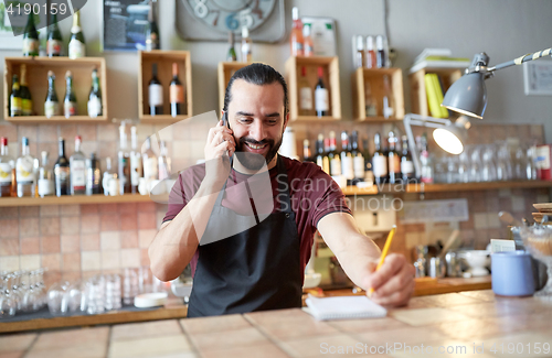 Image of happy man or waiter at bar calling on smartphone